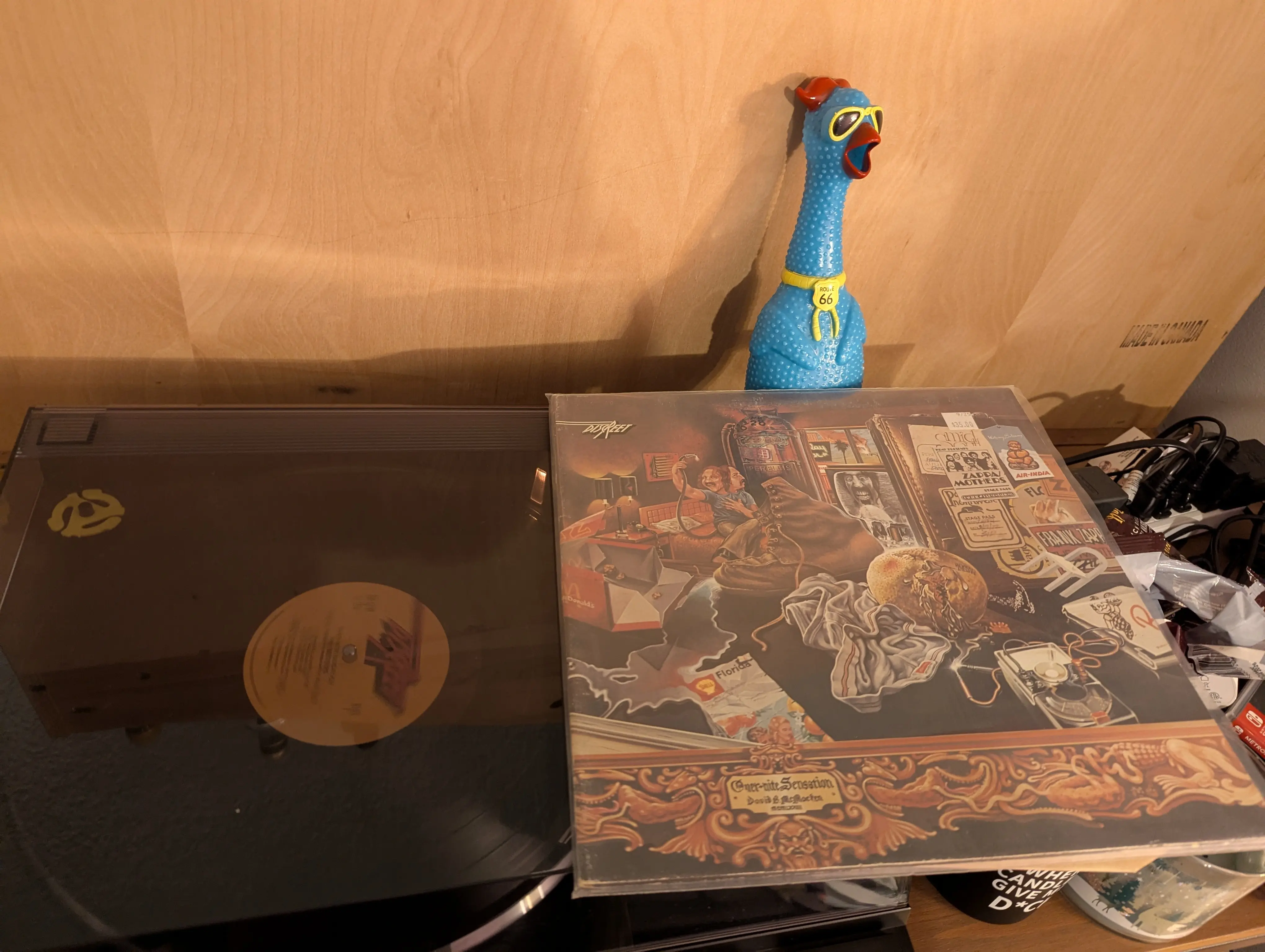 A Frank Zappa and the mothers of invention vinyl playing on a record player, with a blue chicken dog toy in the background. 
